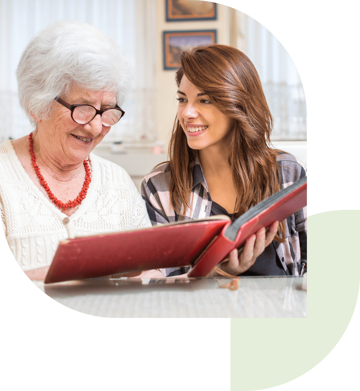 Elderly woman and young woman reading book.